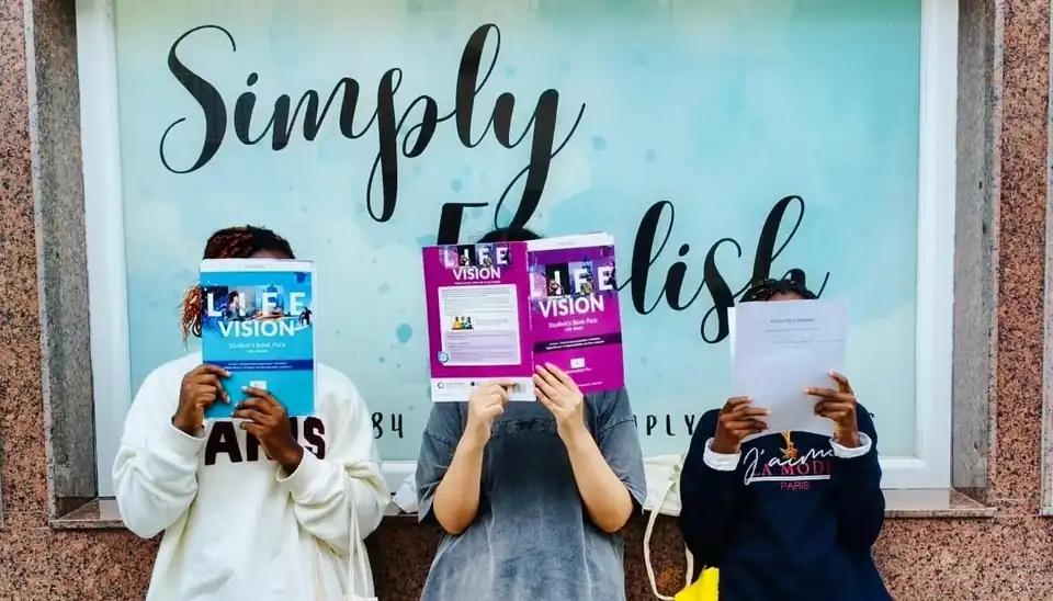 Alumnas de Simply English tapándose la cara con sus libros de inglés